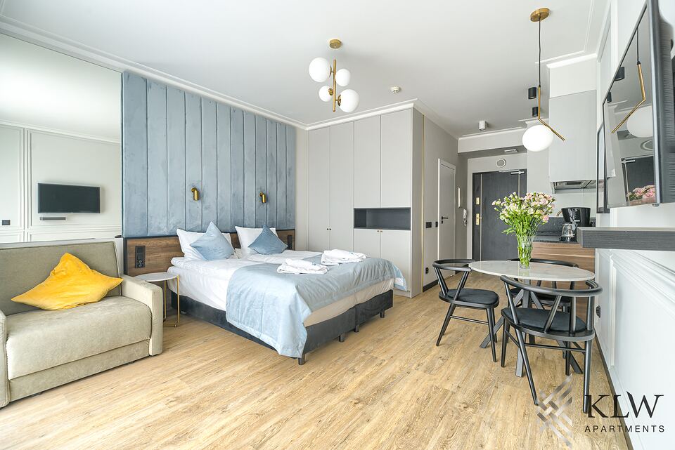 Apartament Lividus 307 w Świnoujściu – widok na całe wnętrze: sofa, łóżko, stół z krzesłami i aneks kuchenny